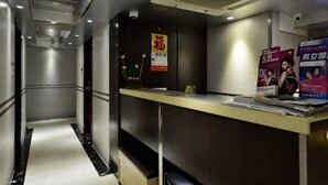 Zona de recepción de un hotel con mostrador, un cartel y una cámara de seguridad.