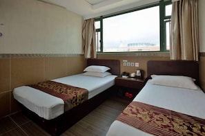 Habitació d'hotel amb dos llits individuals, una taula petita amb una làmpada, una finestra amb cortines i vista a la ciutat.