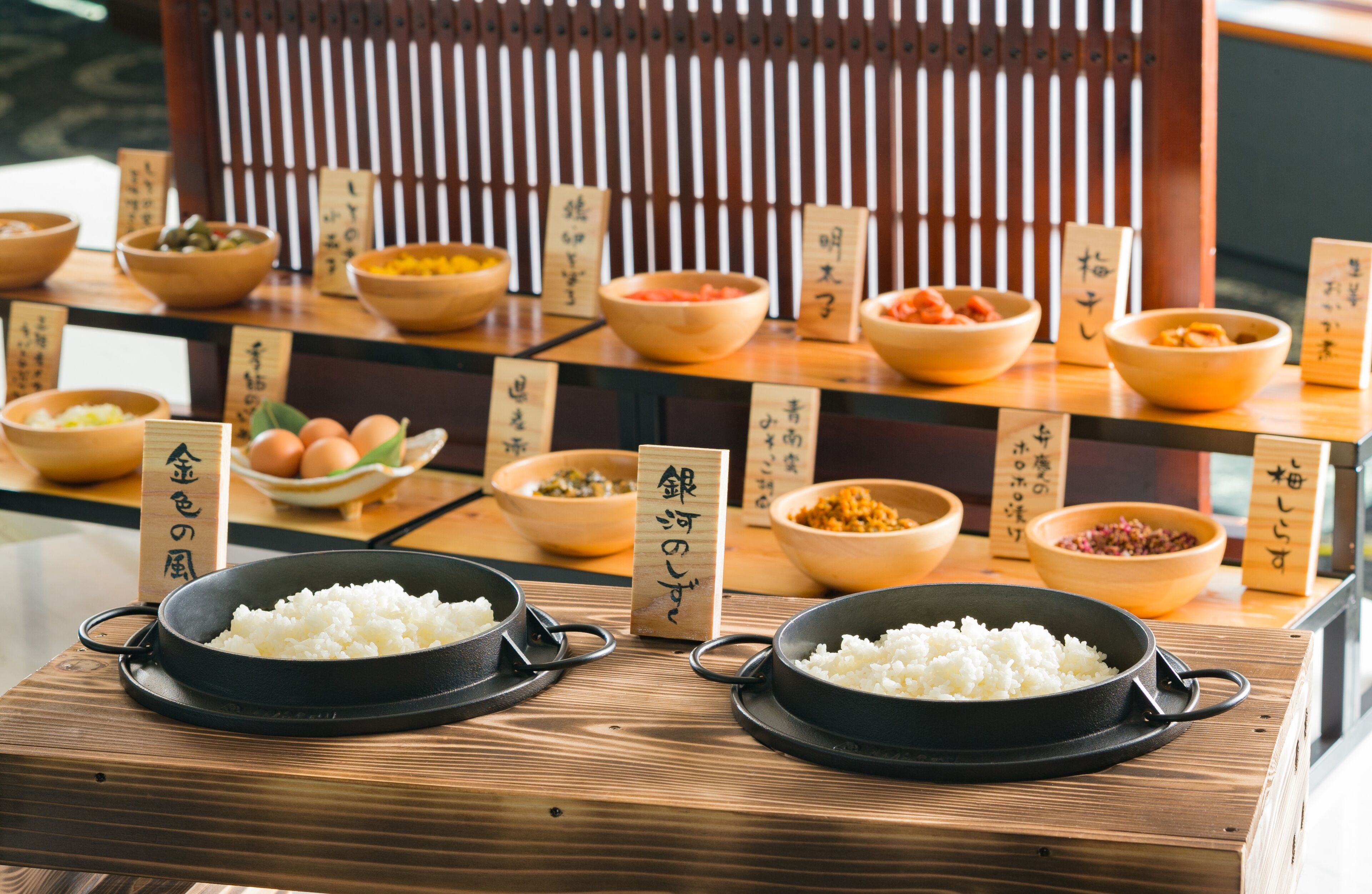 A wooden table with various bowls of food and Japanese labels.