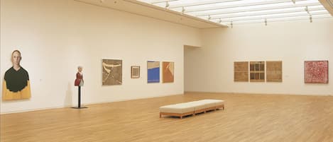 Una galería de arte con pisos de madera y un techo alto.