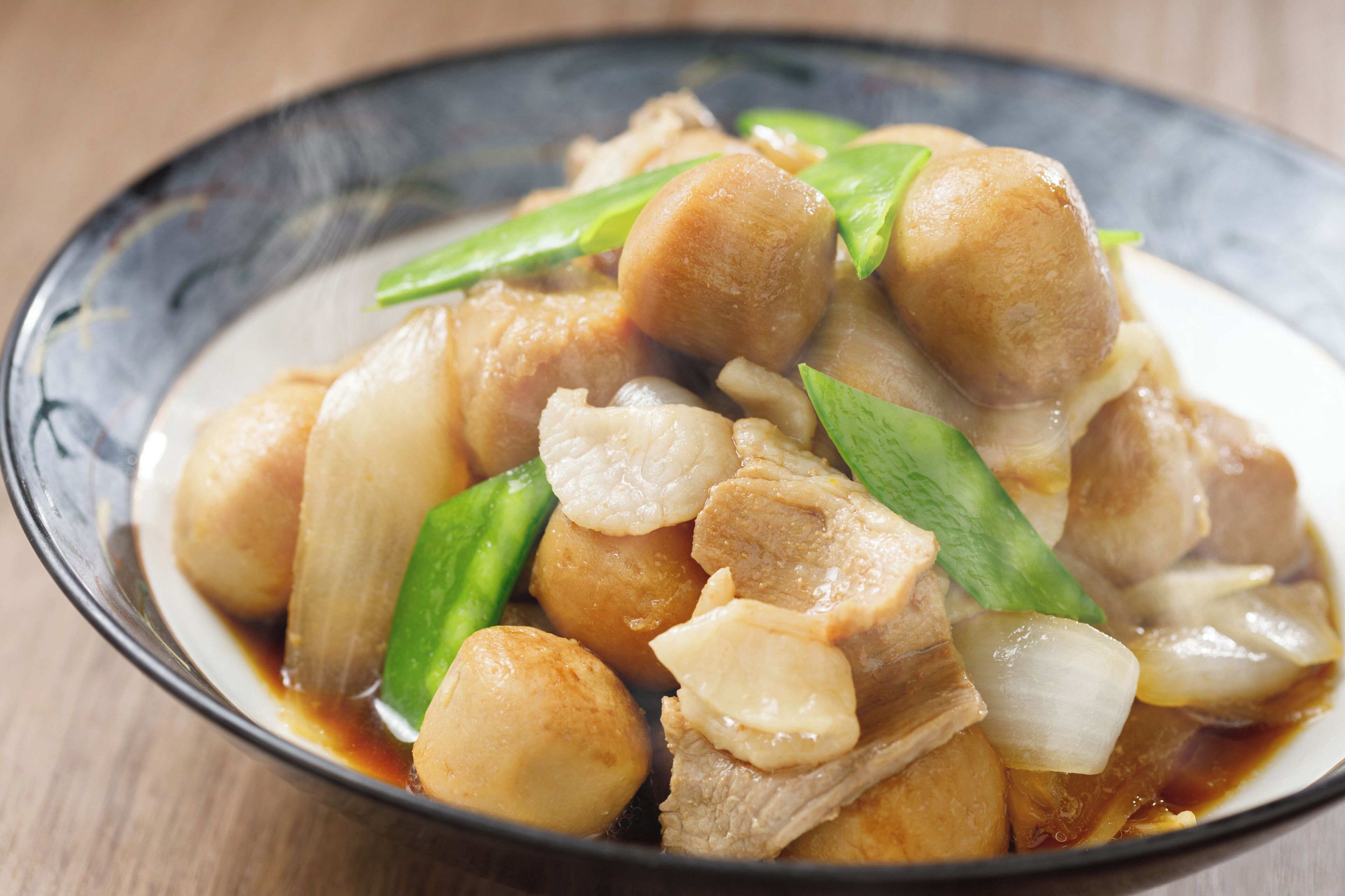 A dish with tofu, green vegetables, and onions in a sauce.