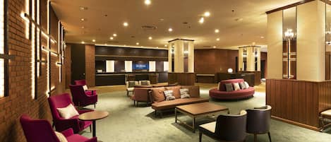 A hotel lobby with seating areas, a reception desk, and a bar.