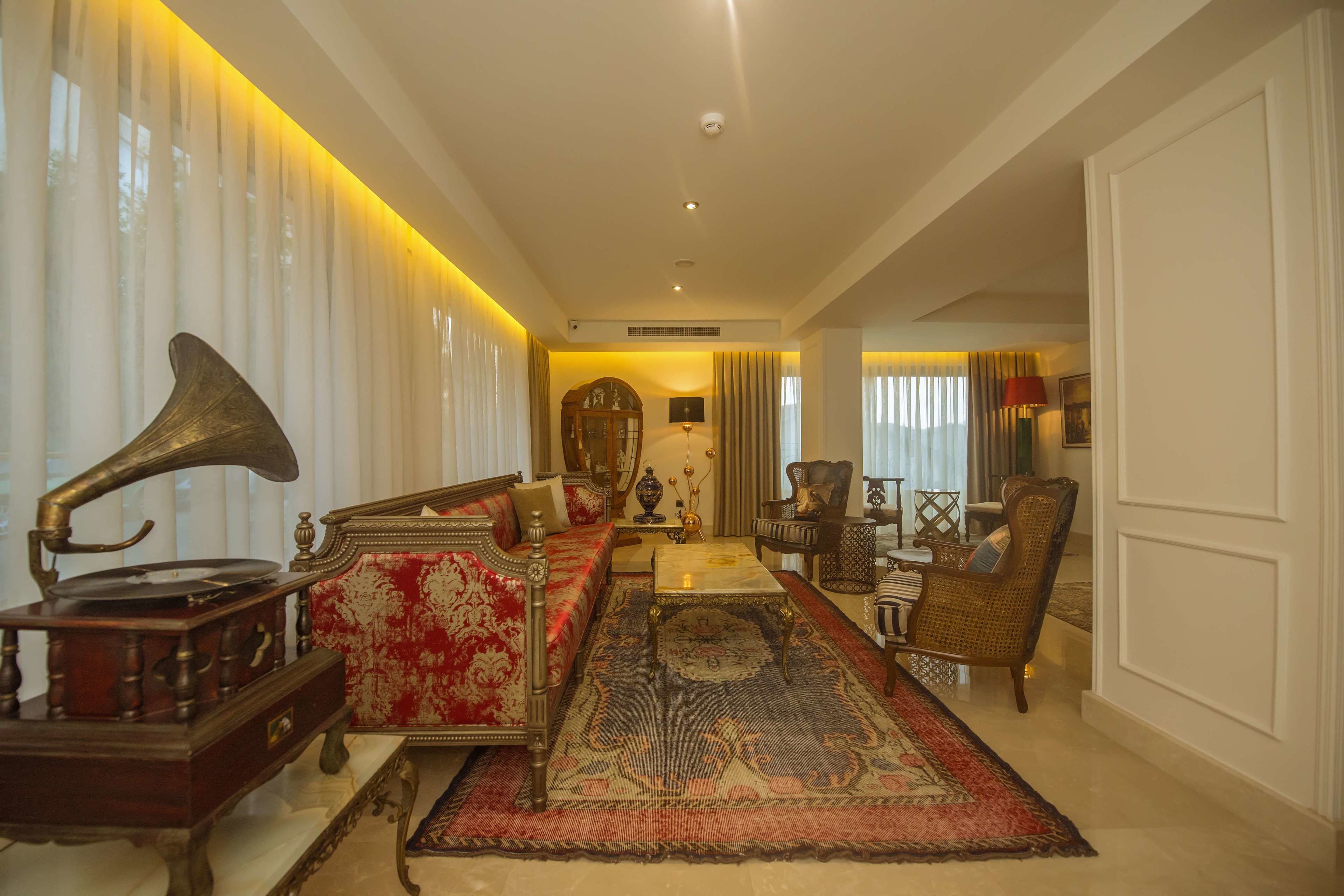 A spacious living room with a vintage gramophone, a red sofa, and a large rug.