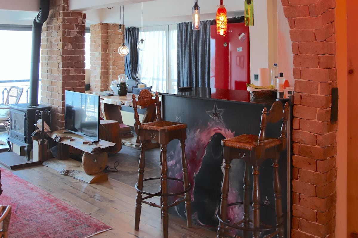 A cozy interior with exposed brick walls, wooden flooring, and a bar area with stools.