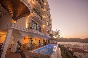 A multi-story hotel with a pool, outdoor seating, and a view of the sea. - Casa Margot Hotel (Fethiye)