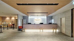 A hotel reception area with a wooden reception desk, a counter, and a seating area with stools. - Smile Hotel PREMIUM SAPPOROSUSUKINO (Sapporo)