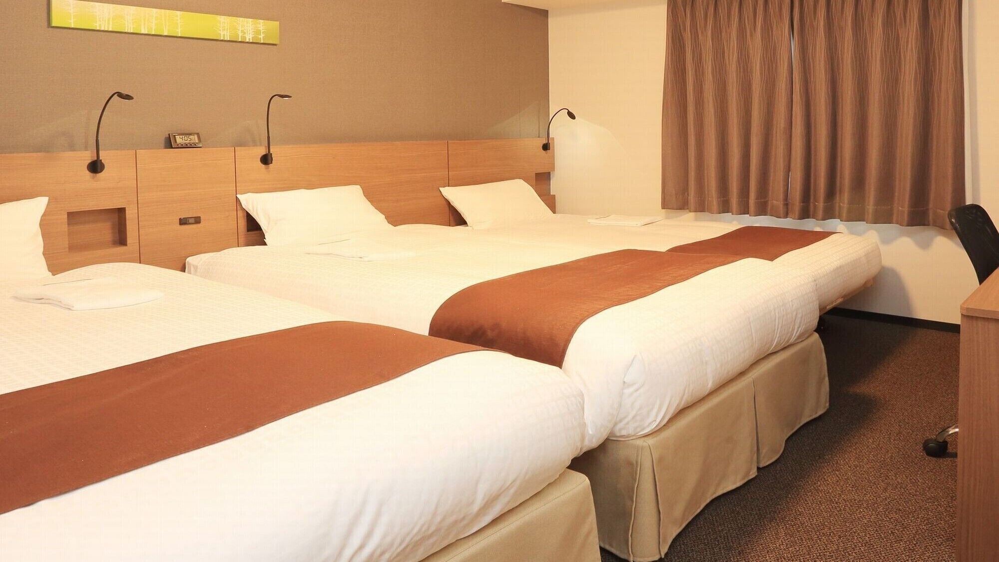 Ein Hotelzimmer mit drei Betten, einem Schreibtisch und einem Stuhl.
