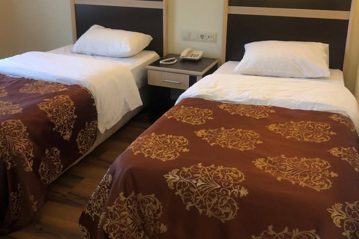 Une chambre d’hôtel avec deux lits simples, chacun doté d’une tête de lit, de tables de chevet et de lampes.