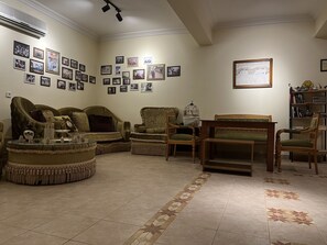 A living room with a sofa, chairs, a coffee table, and a bookshelf. - Nemrut Euphrat Hotel (Kahta)