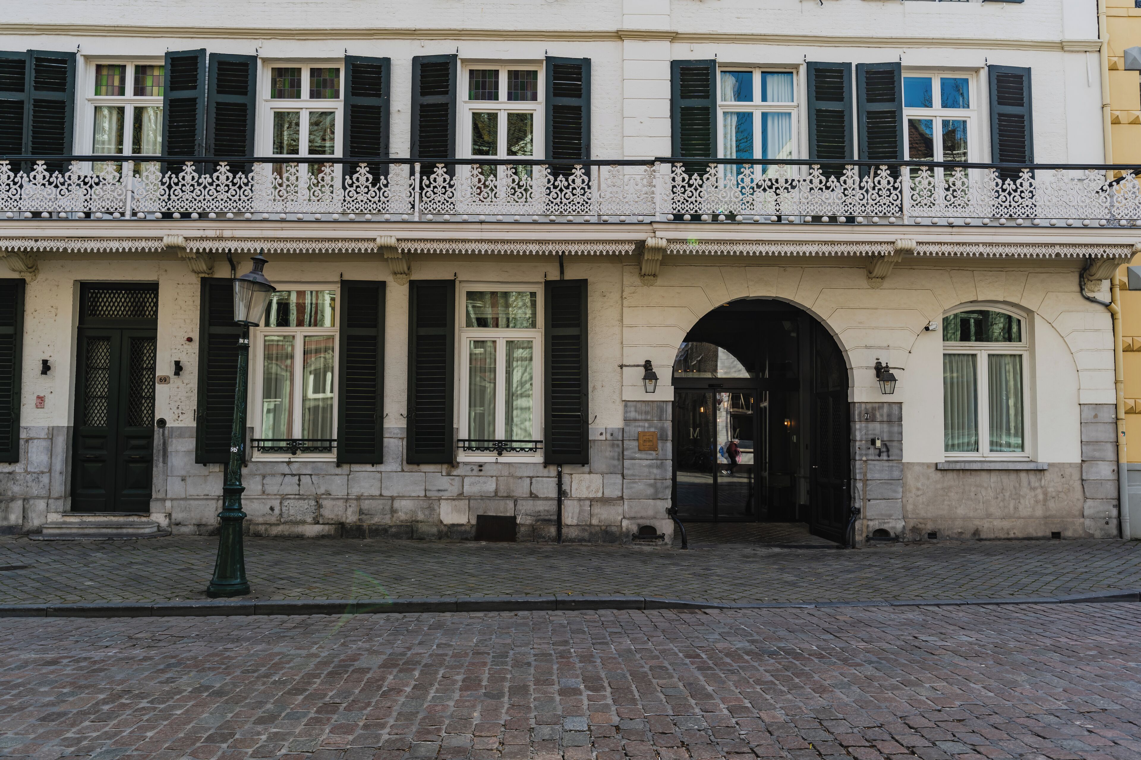 A historic building with a white facade, black shutters, and a decorative balcony.