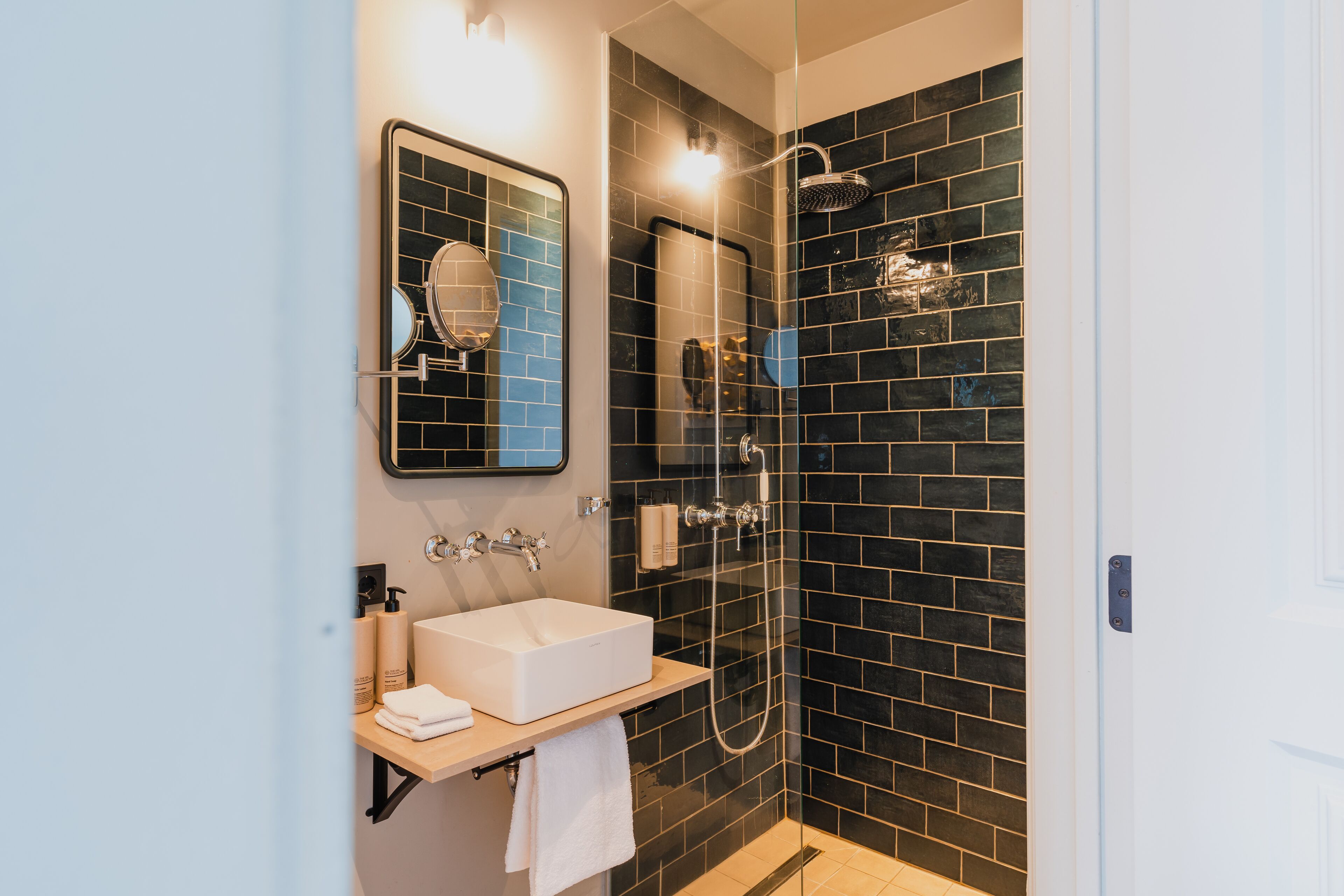 Un baño moderno con un lavabo, espejo y ducha blancos.