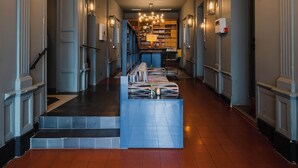 Un hall d’entrée spacieux, doté d’un escalier central, d’un éclairage décoratif et d’un présentoir à magazines.