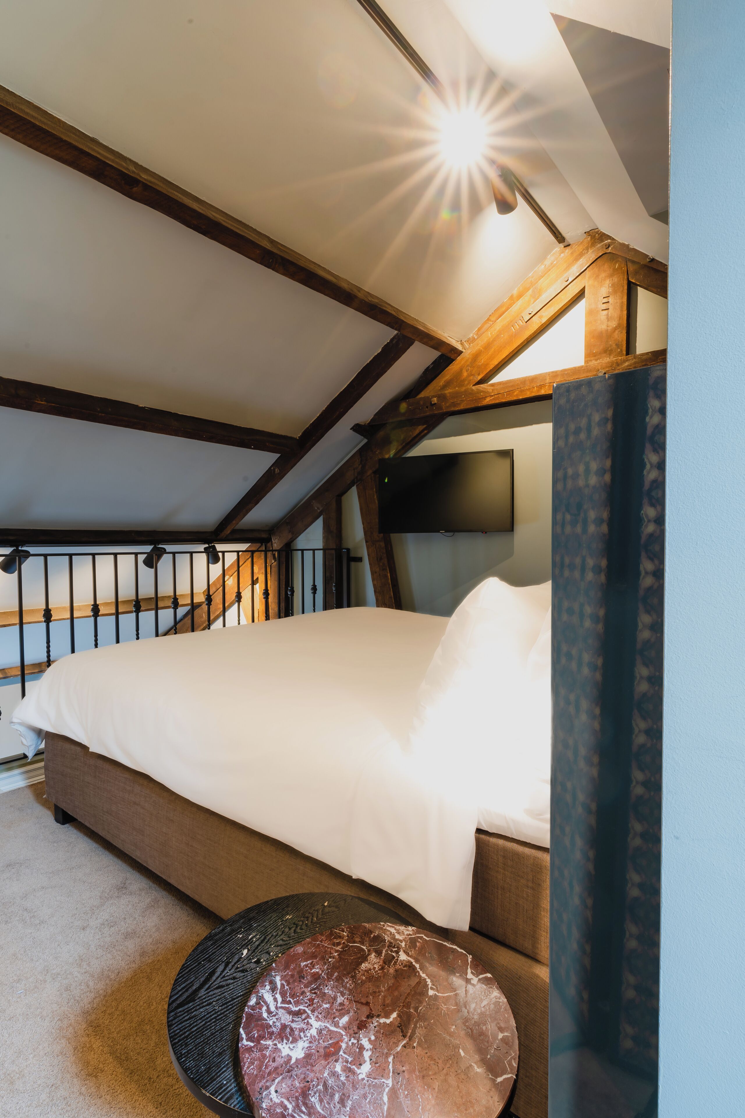 Une chambre à coucher avec un lit, un téléviseur fixé au mur et un plafond en bois.