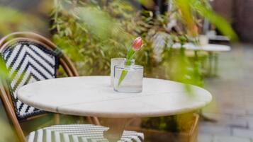 Une table ronde sur laquelle est posé un vase en verre contenant une seule tulipe rouge.