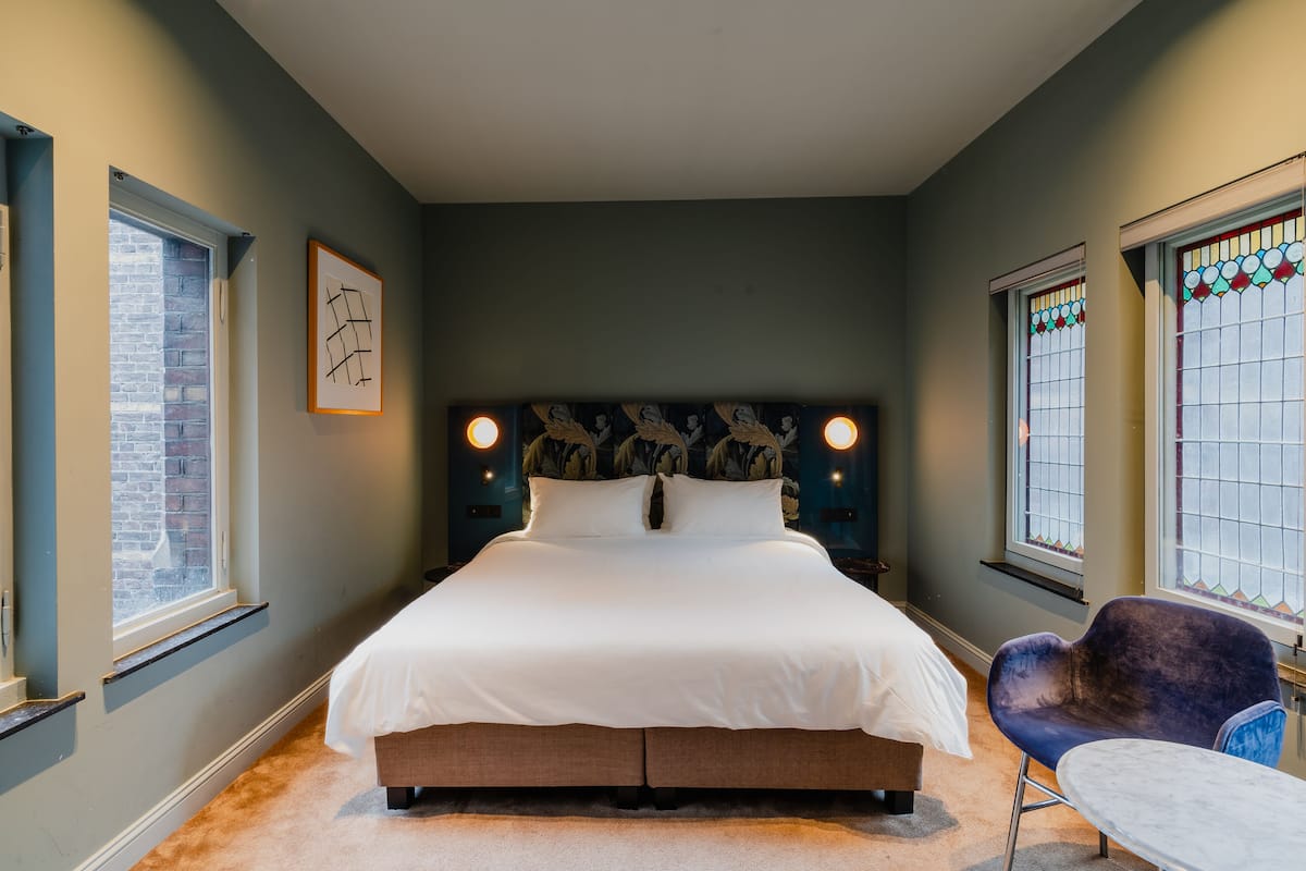 Une chambre avec un grand lit, une chaise et une table.