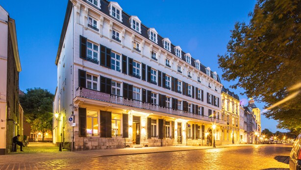 Un bâtiment historique à étages, doté de grandes fenêtres et d’un balcon.