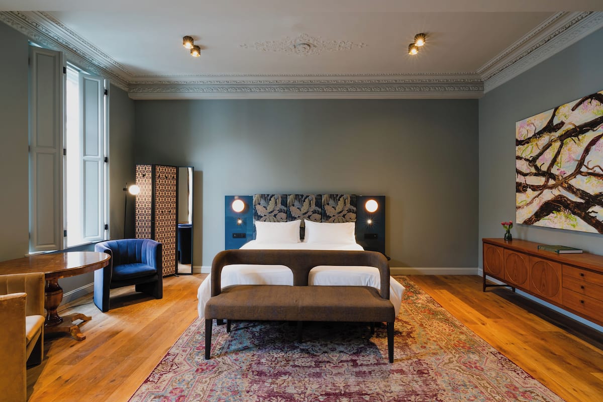 Une chambre avec un grand lit, un banc, un bureau et une chaise.