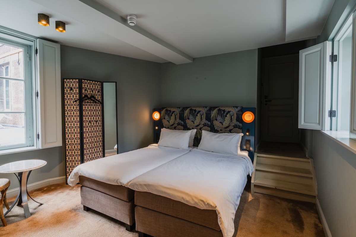 Une chambre à coucher avec un lit, des lampes de chevet, une petite table et une fenêtre.