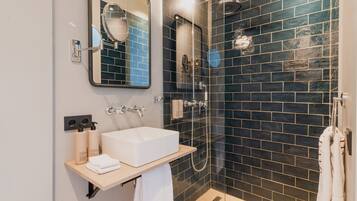 Een moderne badkamer met een wit wastafelmeubel, spiegel en een douchewand betegeld met zwart.