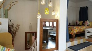 A room with a bed, a sofa, a dining table, and a mirror. - Ban Thor Phan (Sangkhla Buri)