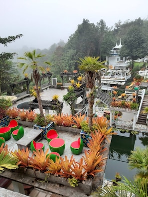 A rooftop garden with seating areas and a view of a temple in the background.