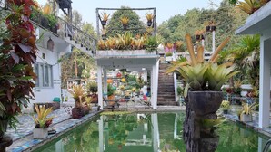 A pool area with a tiled deck, surrounded by potted plants and a staircase leading to a covered upper level. - Ban Thor Phan (Sangkhla Buri)