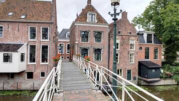 A canal-side walkway with brick buildings, a small bridge, and a lamp post.