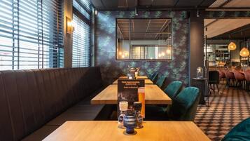 Un interior de restaurante con una mesa de madera, asientos acolchados y piso de tablones.