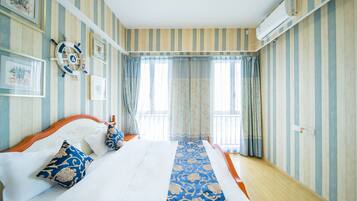 A hotel room with striped wallpaper, a bed with white linens, blue and gold pillows, and a decorative wall hanging.