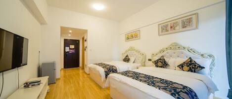 A hotel room with two beds, a TV, a small fridge, and a desk.