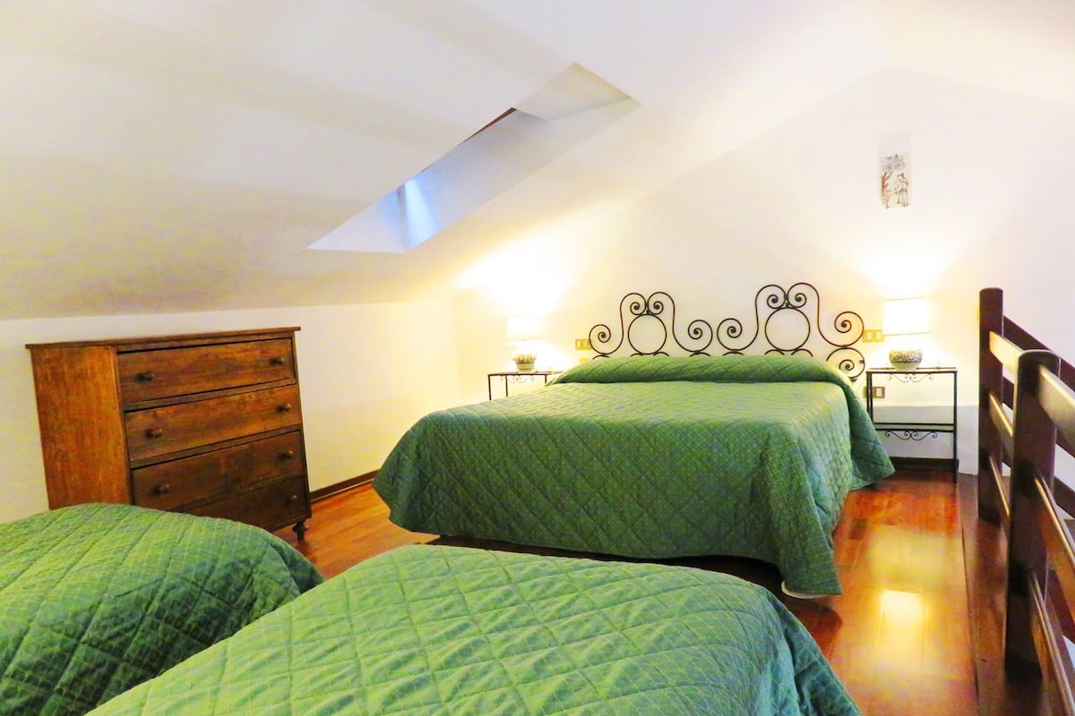 Un dormitorio con dos camas, un aparador de madera, un tragaluz y una mesita de noche con lámpara.