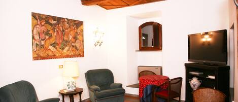 Una sala de estar con techo de madera, un cuadro, un televisor y una mesa con mantel rojo.
