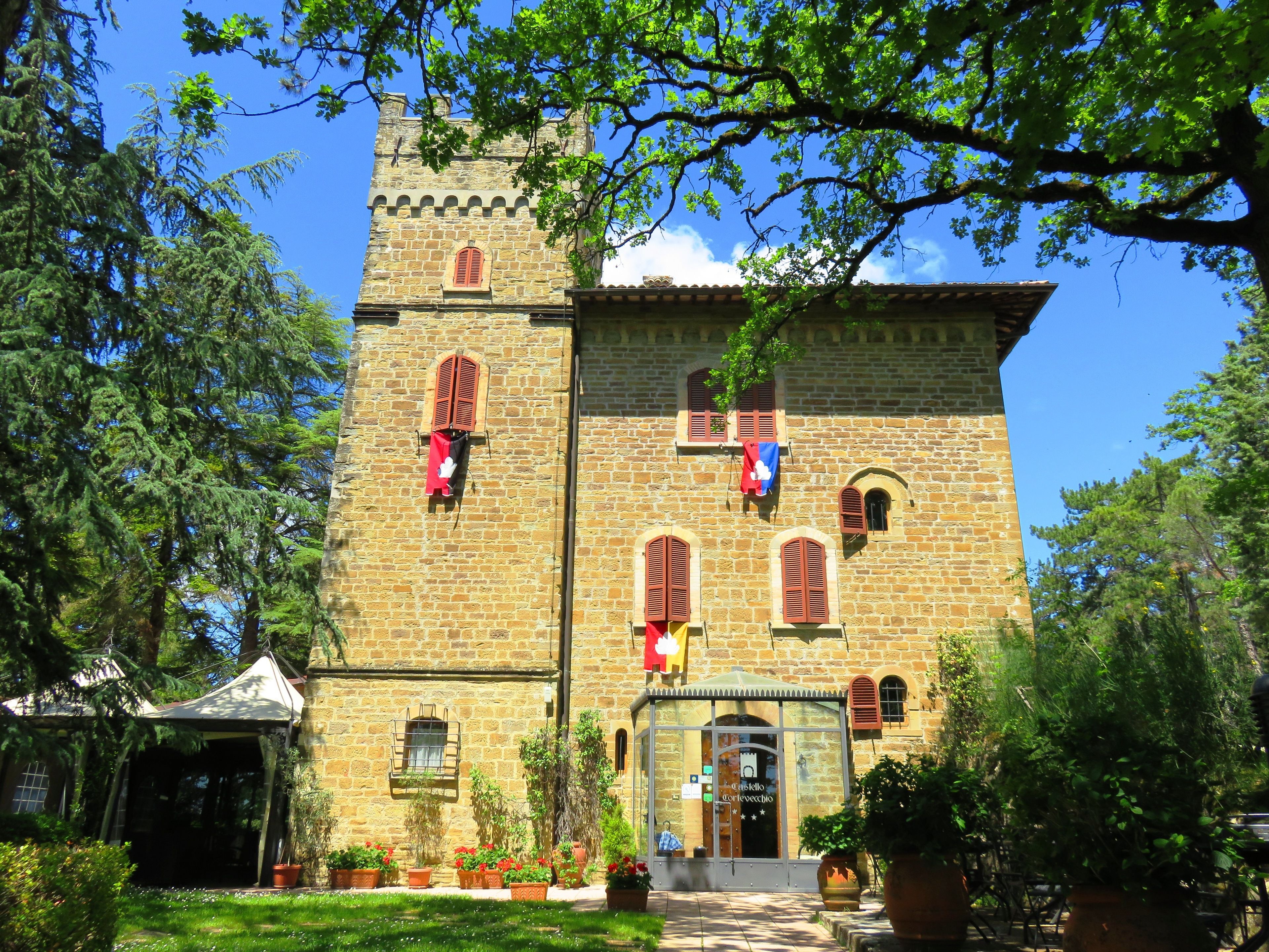 A stone building with a tower, arched windows, and a covered entrance.