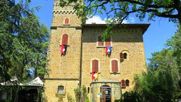 A stone building with a tower, arched windows, and a covered entrance.