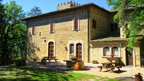 A stone building with arched windows and a tiled roof. - Castello Cortevecchio (Gubbio)