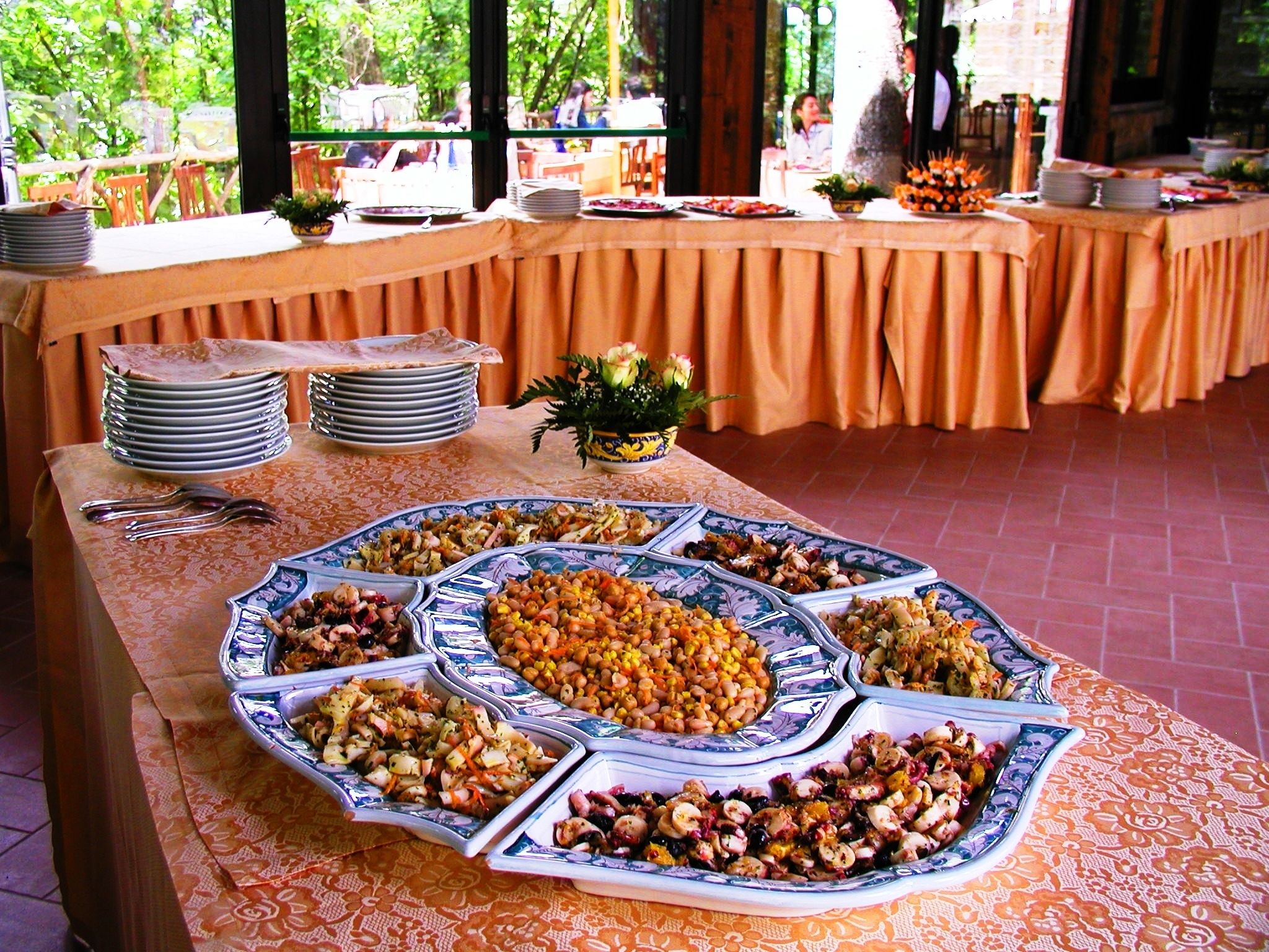 A buffet table with various dishes and plates.