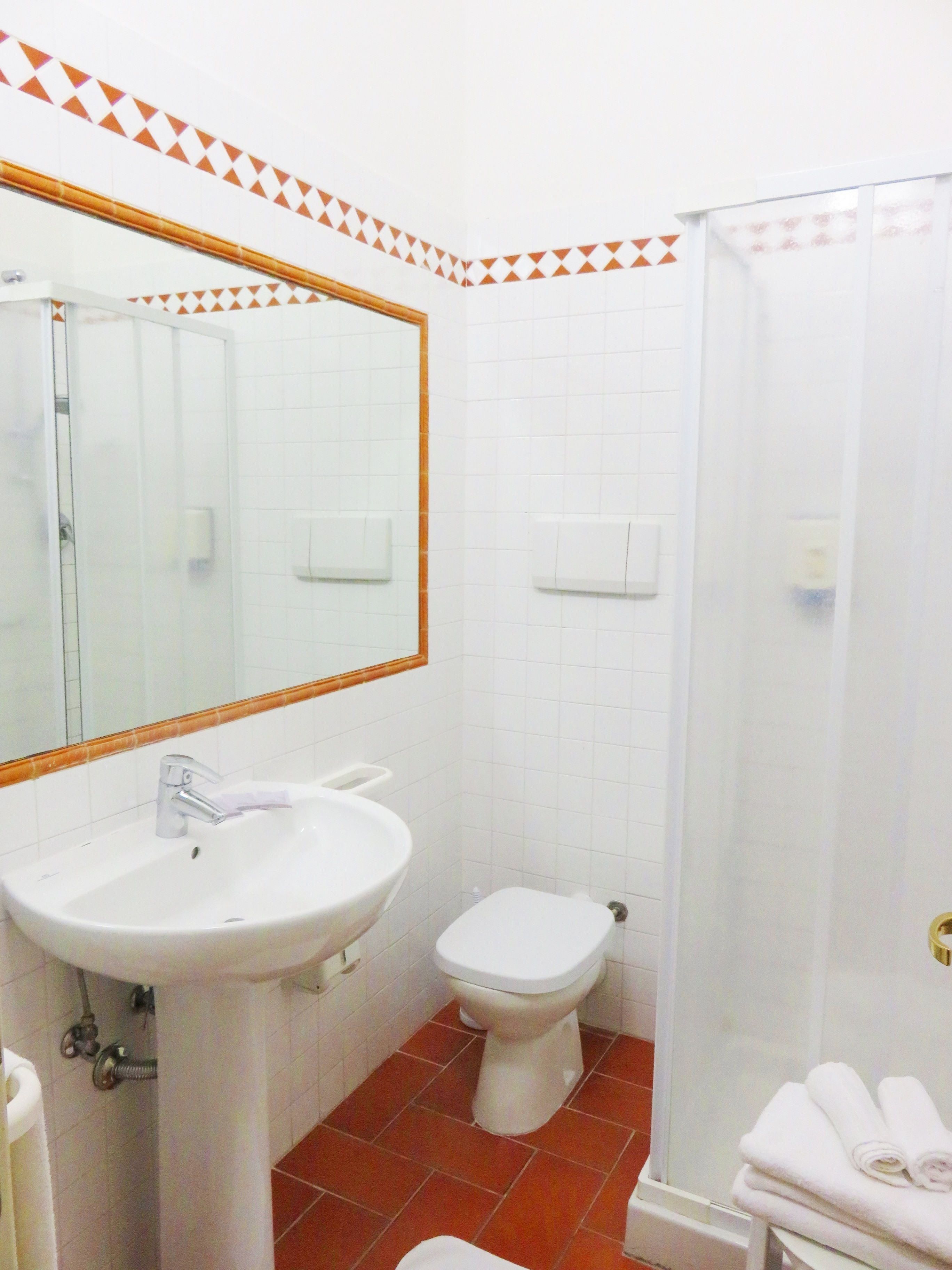 Un baño con lavamanos blanco, inodoro y ducha.