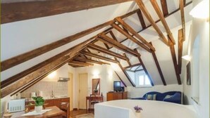A cozy attic bedroom with a sloped ceiling, a bed, a desk, and a chair. - Apartments Vi-La (Dubrovnik)