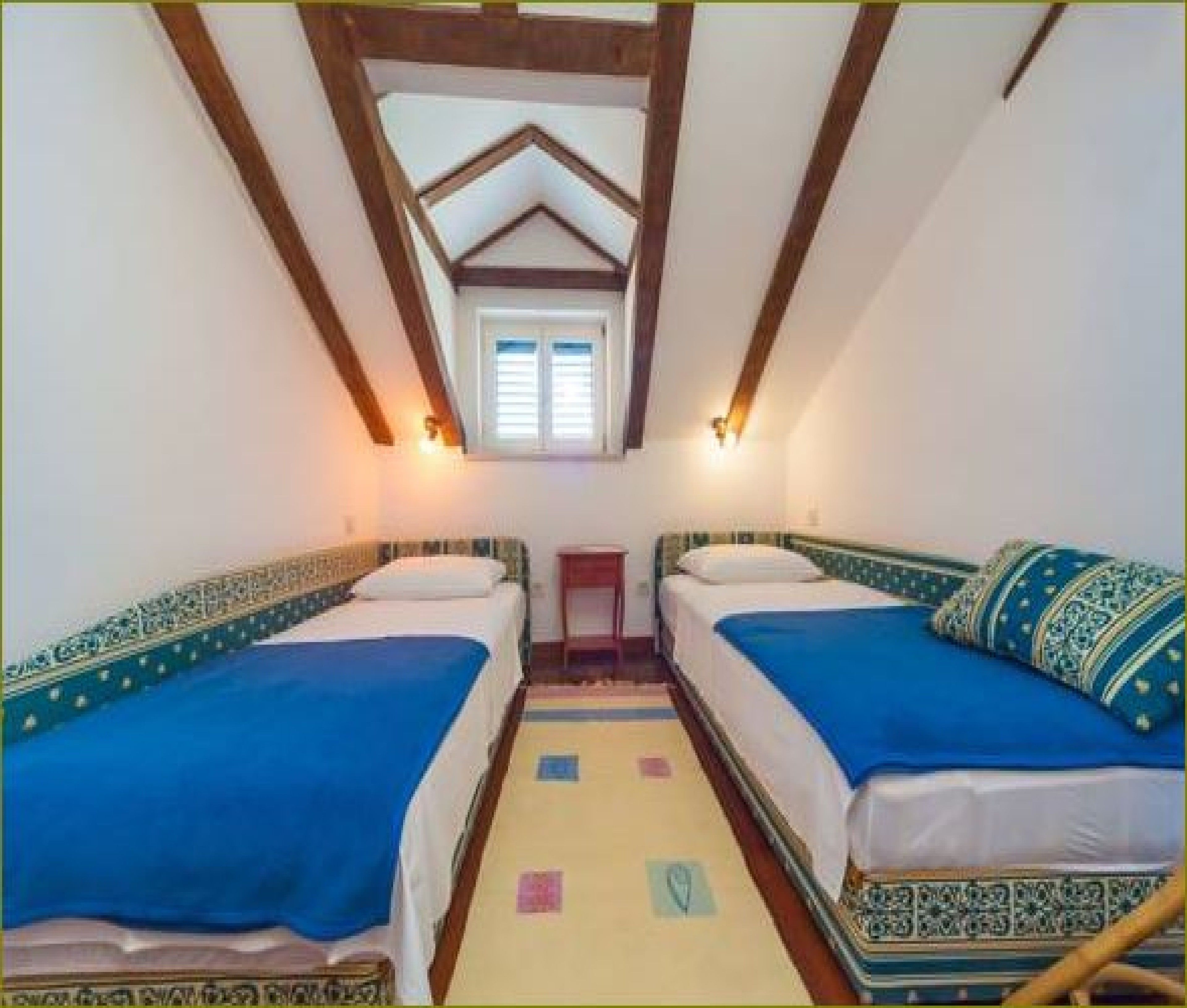 Een kamer met twee bedden, een tafeltje en een raam.