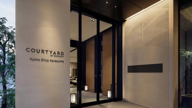 A modern hotel entrance with a glass door, a sign reading "COURTYARD BY MARRIOTT Kyoto Shijo Karasuma," and a view of the interior through the glass. - Courtyard By Marriott Kyoto Shijo Karasuma (Kyoto)