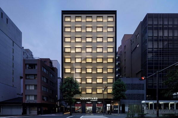 Un hotel moderno con una fachada de ventanas en forma de cuadrícula, una entrada visible y un cartel que dice "Courtyard by Marriott".