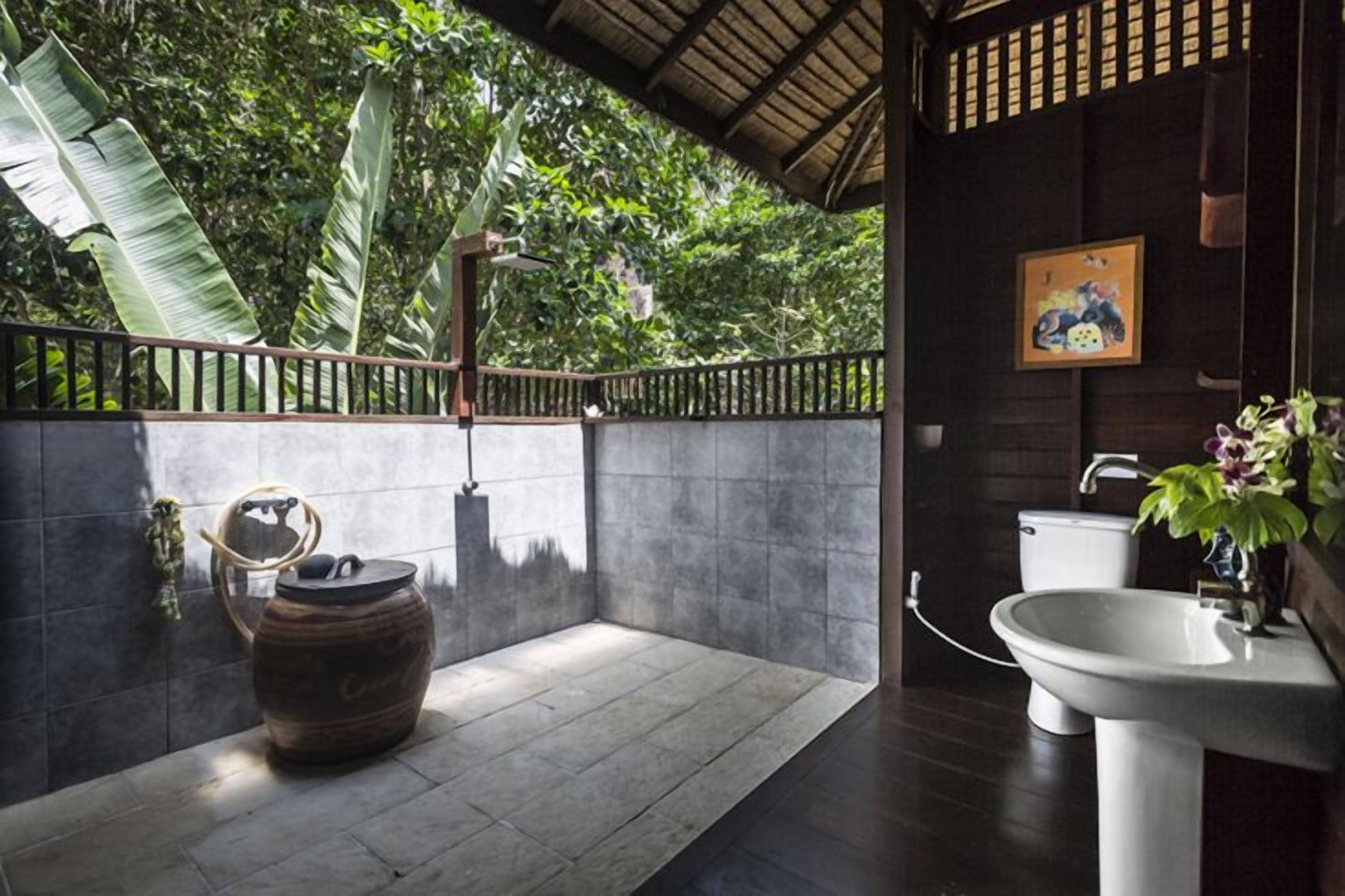 A bathroom with a large wooden door, a white sink, and a shower area with a wooden barrel.