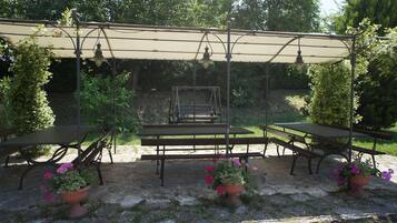An outdoor patio with a covered seating area, tables, and potted plants.