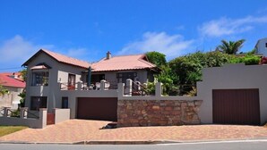 A two-story house with a red-tiled roof, a stone wall, and a gated driveway. - Admirals Rest Self-Catering House (Mossel Bay)