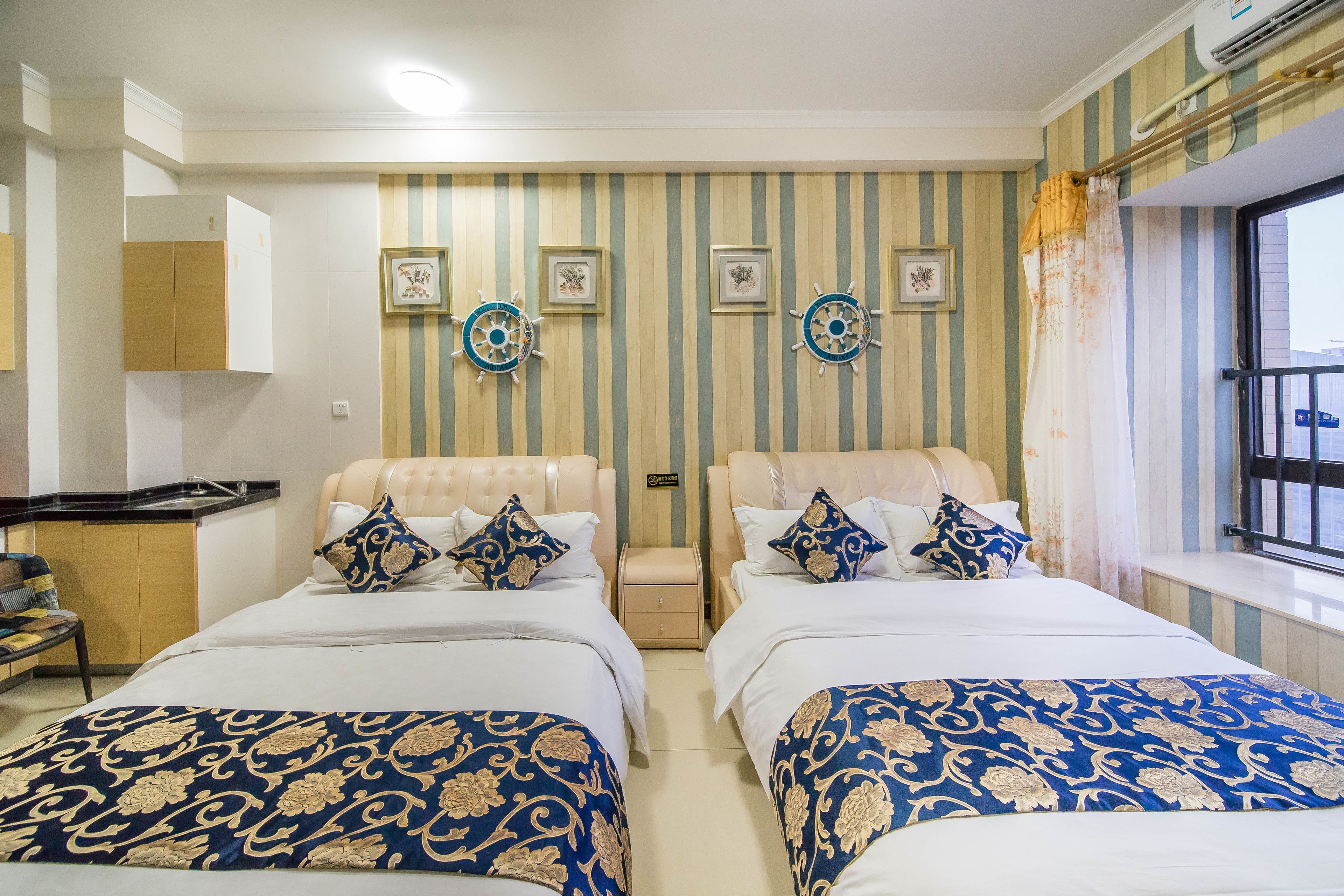 Une chambre d’hôtel avec deux lits, un papier peint à rayures et des éléments de décoration murale sur le thème de la marine.