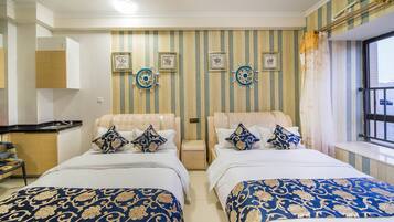 A hotel room with two beds, striped wallpaper, and nautical-themed wall decor.