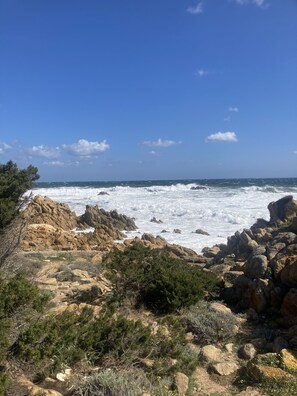 A rocky coastal landscape with waves crashing against the shore, under a clear blue sky. - Hotel L'Ancora (Siniscola)