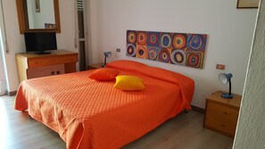 A room with a bed, a desk, a chair, a lamp, and a painting on the wall. - Hotel L'Ancora (Siniscola)