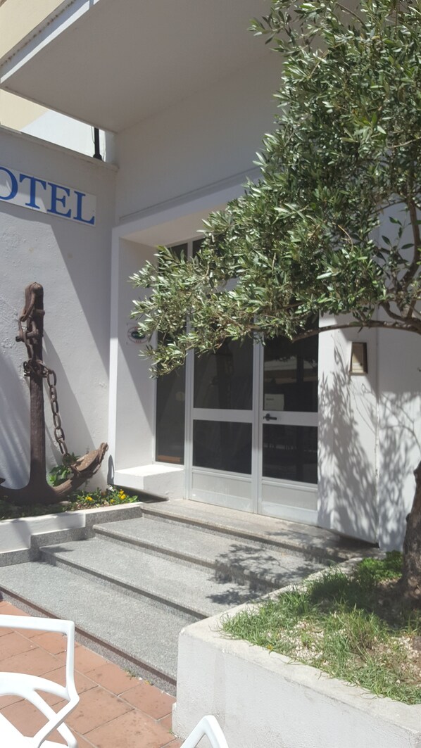 A hotel entrance with a sign, steps, and a tree. - Hotel L'Ancora (Siniscola)