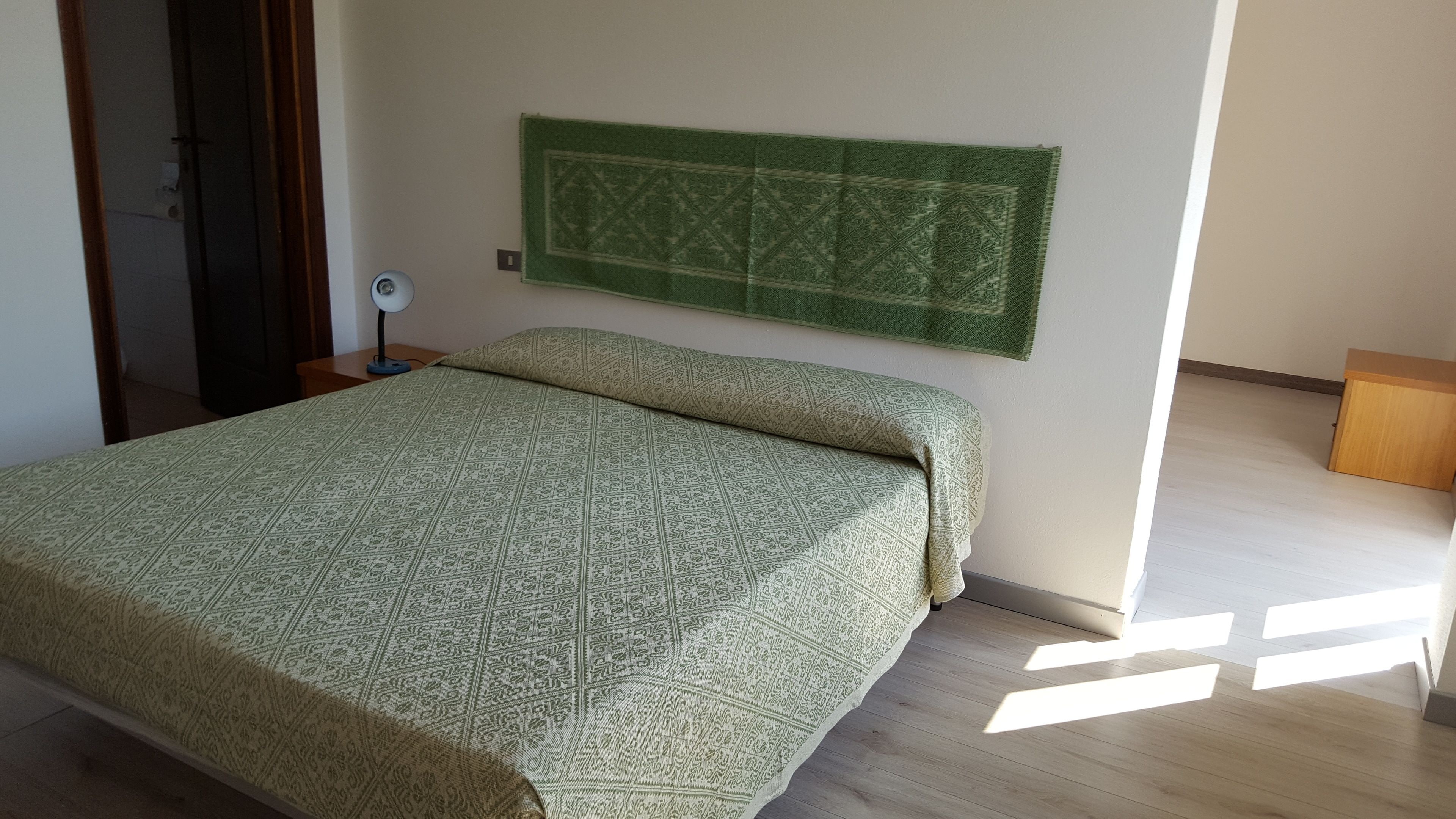 Une chambre à coucher avec un lit, une table de chevet, une lampe et une tête de lit verte.